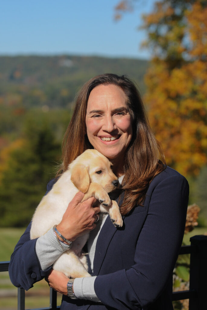 Karen Leis holding a yellow Lab puppy.