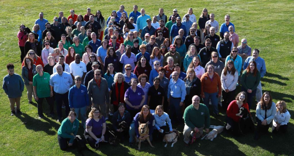 A group photo of dozens of Seeing Eye staff members on the front lawn of the main campus.