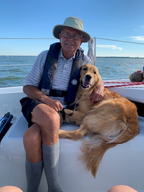 A Seeing Eye graduate sits on a boat with his Seeing Eye dog, a golden retriever, at his side.