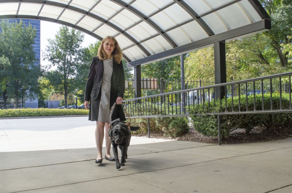 A Seeing Eye graduate being guided by her Seeing Eye dog, a black Labrador/golden retriever cross.