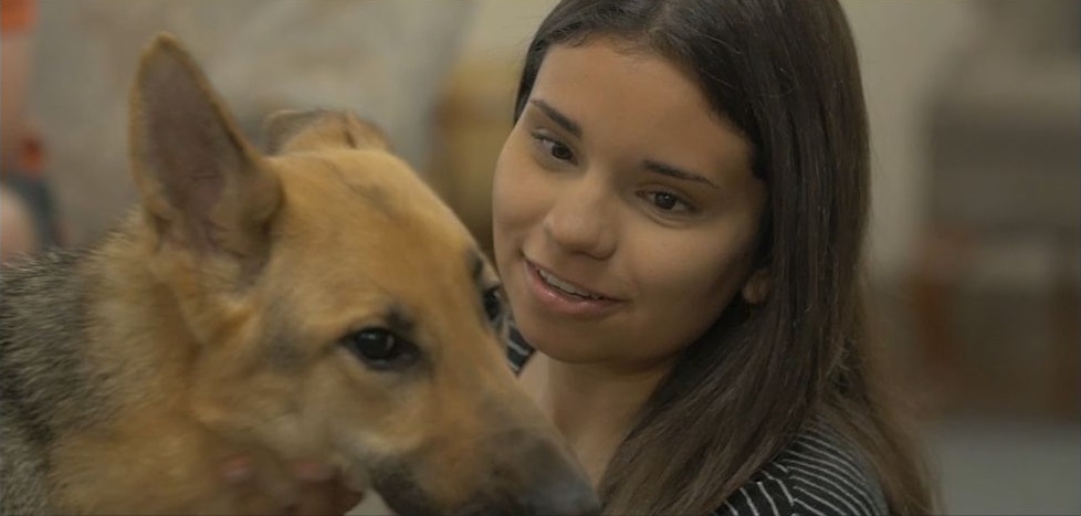 screen shot of a young woman with a german shepherd with a play button.