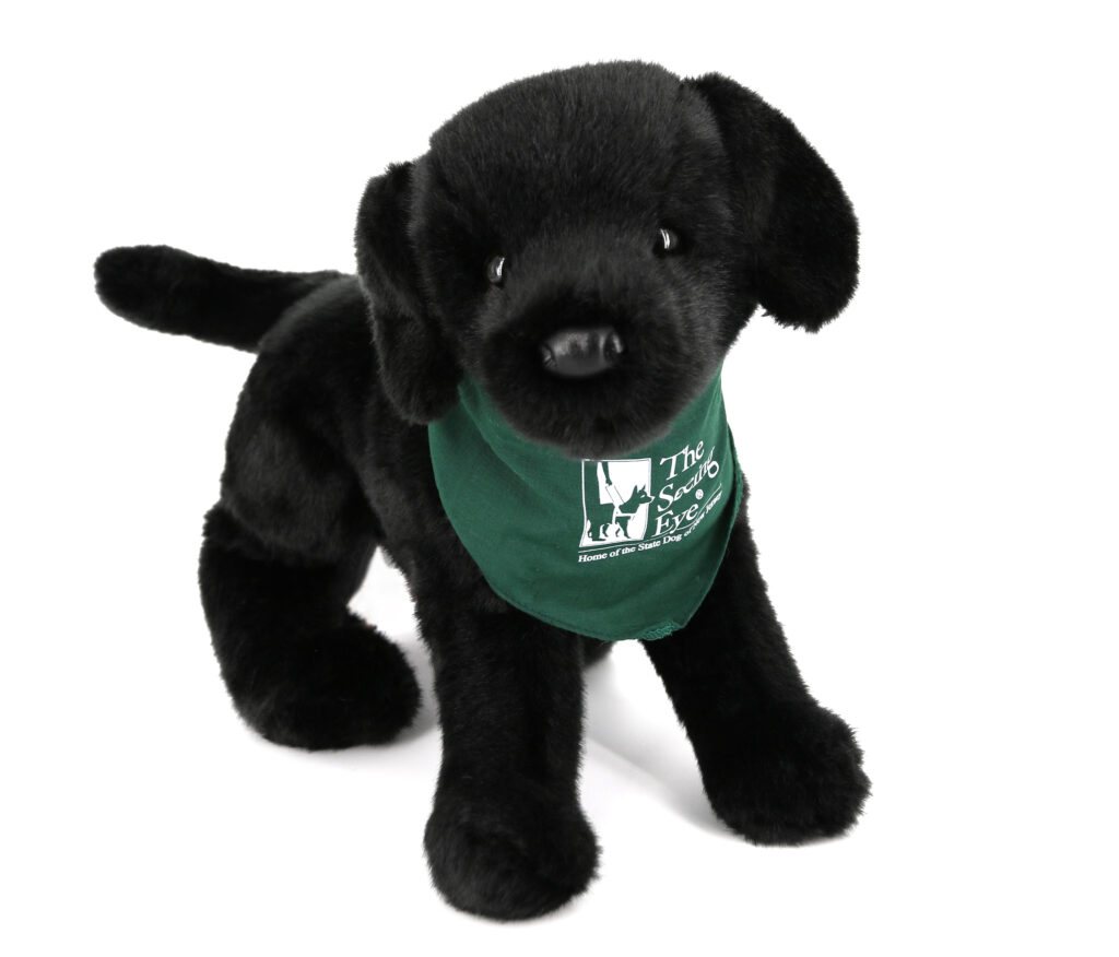 A 16 inch black Labrador retriever plush puppy, with a green bandana with The Seeing Eye logo in white.