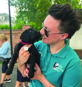 The Seeing Eye's Lauren Christie holding a black Labrador retriever puppy.