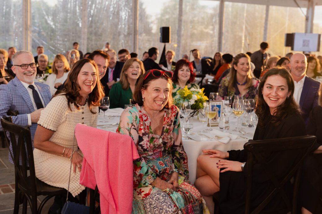 Guests at a table smile and laugh while enjoying the Gala's program.