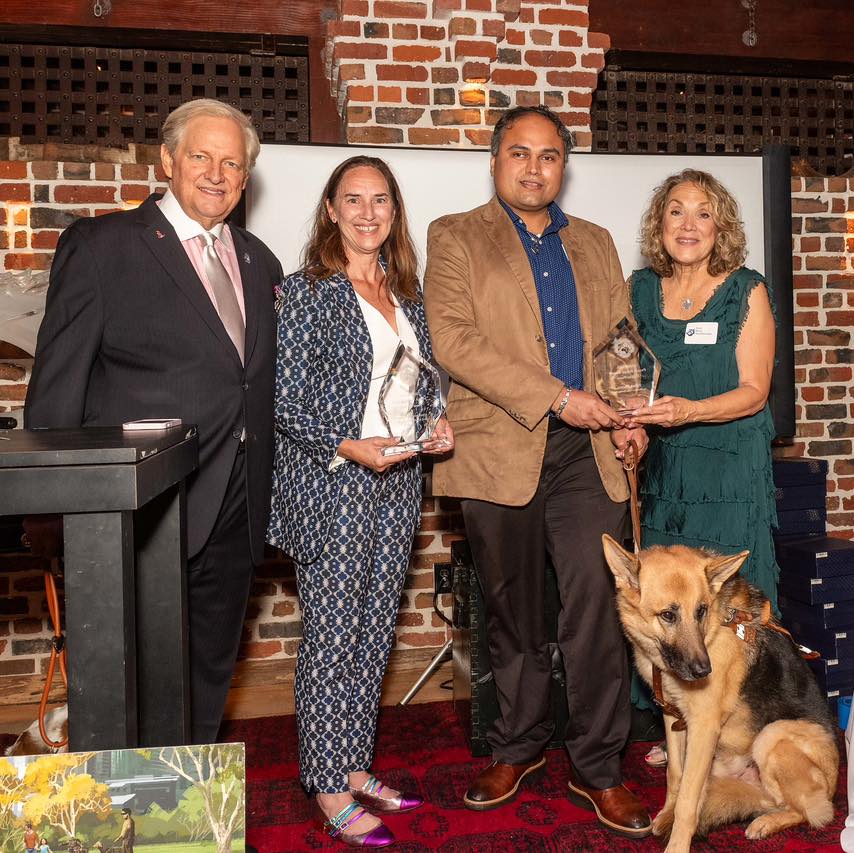 Karen Leies, Seeing Eye President & CEO, and Vinay Billimoria, Seeing Eye graduate, hold National Service Animals Memorial Hall of Fame Awards as two National Service Animals Memorial Hall of Fame representatives beside them. Vinay’s German shepherd Seeing Eye dog, Pluto, sits beside him.