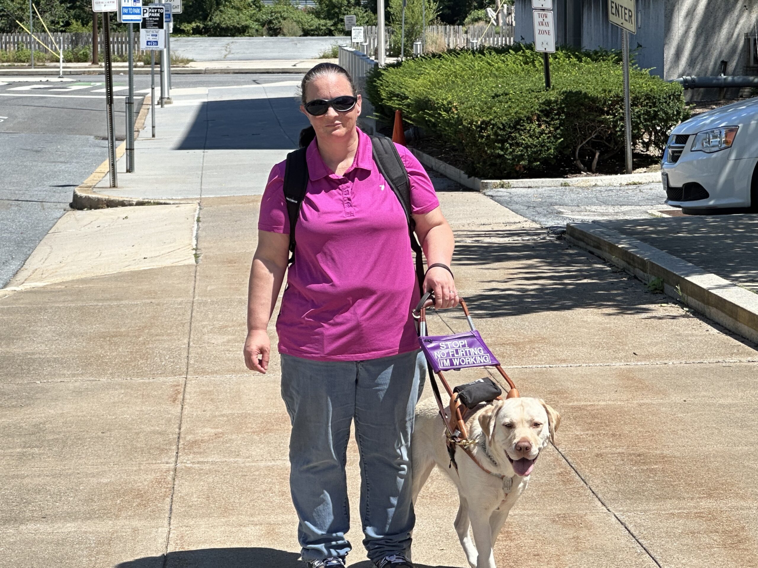 Seeing Eye graduate Milissa walks down the sidewalk during her commute to work with her yellow Lab/golden retriever cross Seeing Eye dog Ruffles.