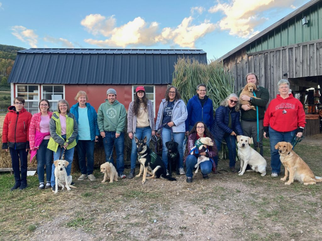Twelve members of the Luzerne County club stand together with three yellow Labs, three golden retrievers, a black and tan German shepherd, and a black Lab, after a visit to the local pumpkin patch in the fall.