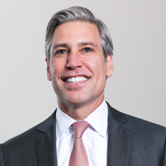 A photo of Chris Valerio wearing a dark suit.